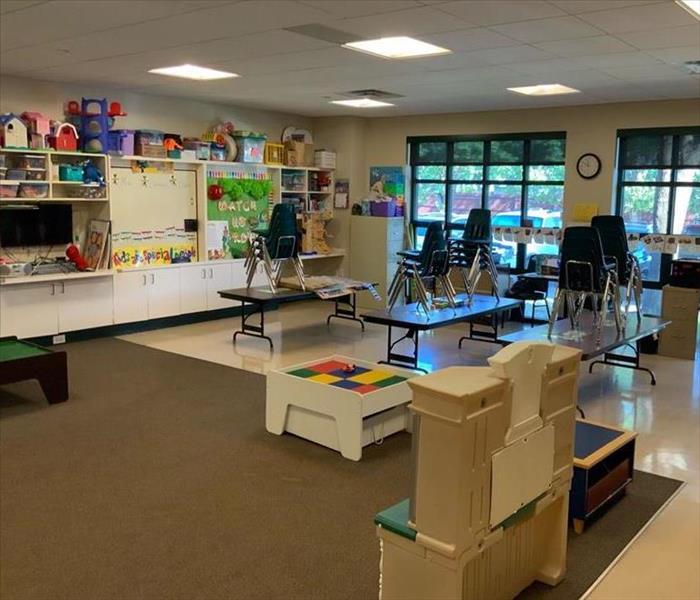 School classroom with dry carpet and clean tile flooring. Chairs are stacked on top of the kids desks. 